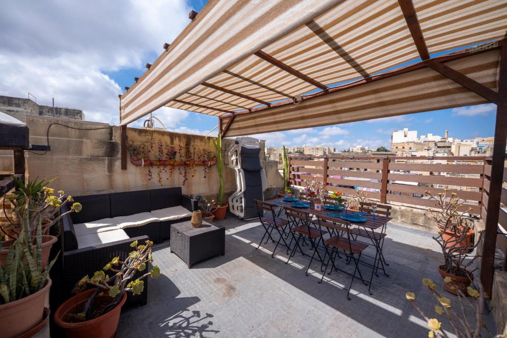 a patio with a table and chairs on a roof at 3Cities Maison close to Valletta in Cospicua