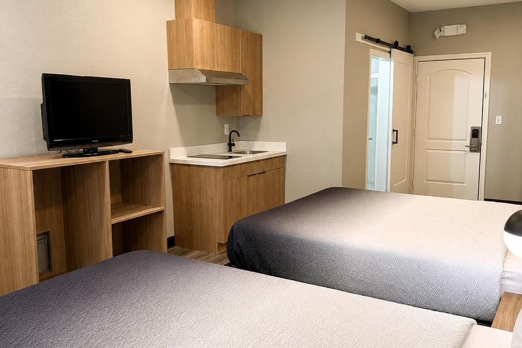 a small room with two beds and a television at Super 8 by Wyndham Brenham TX in Brenham
