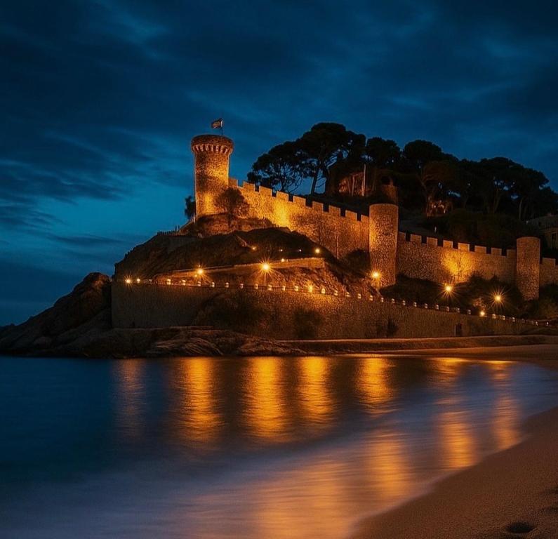 a castle with a lighthouse on a hill next to the water at Casita de Mar in Tossa de Mar