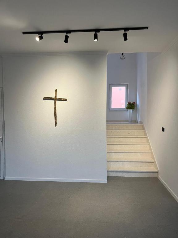 a cross on a wall in a room with stairs at Apartmani KIKO in Međugorje