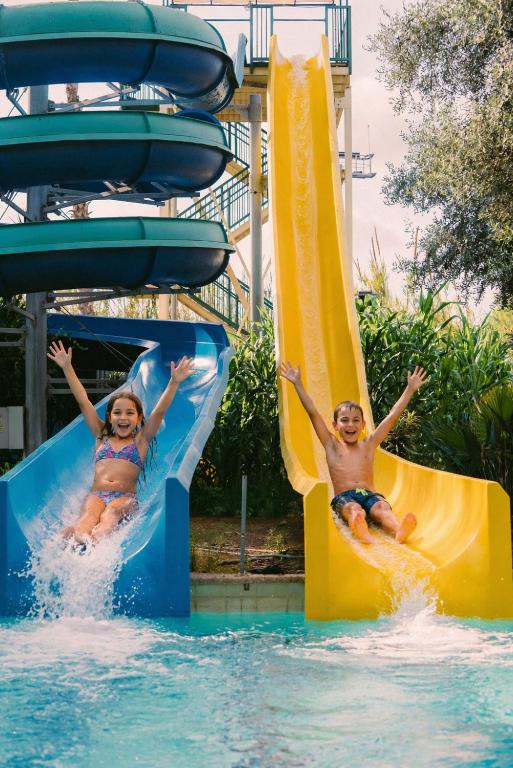 two children sliding down a water slide at a resort at Kfar Maccabiah Business & Sport Hotel in Ramat Gan