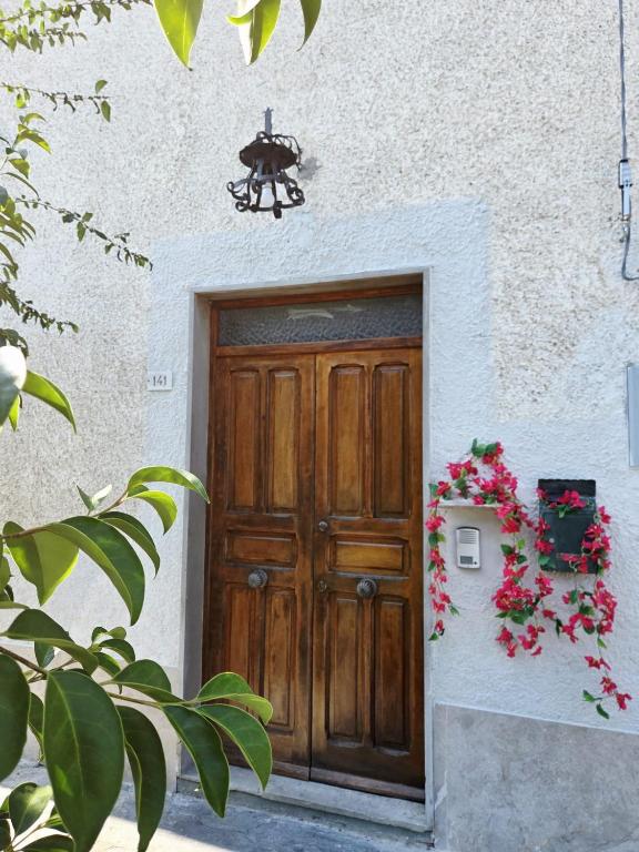 a wooden door on a white building with flowers at FasHion HOme in Ameglia