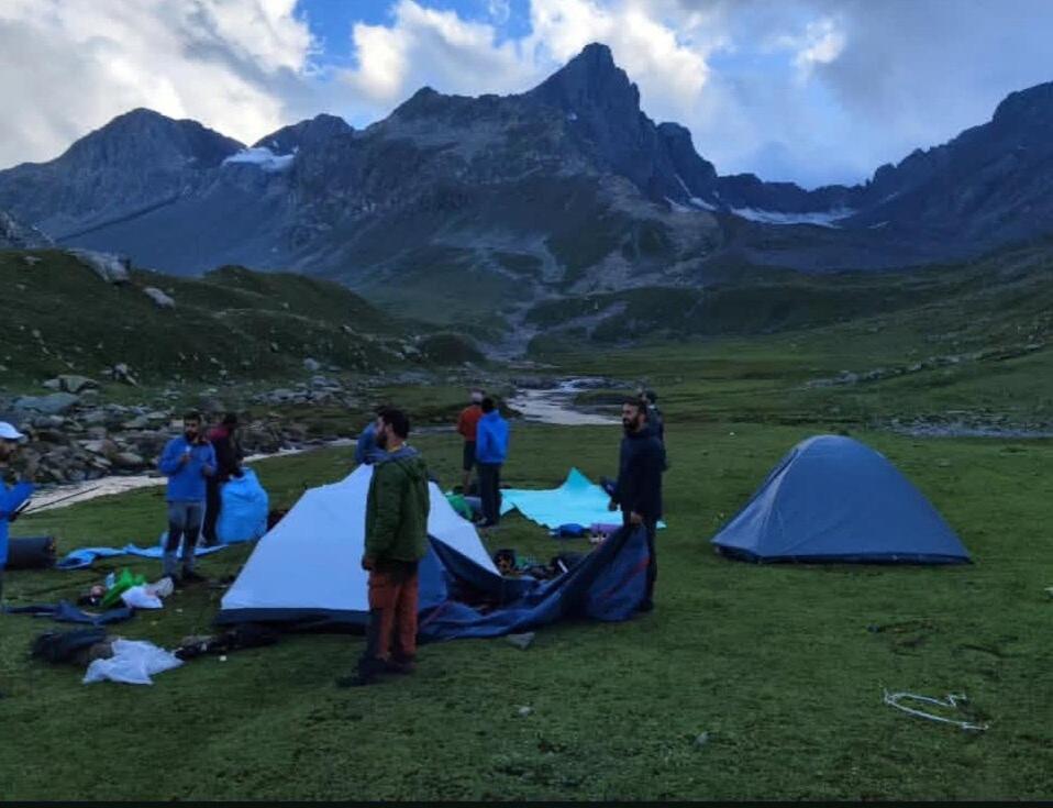 a group of people standing around tents in a field at Khan Camping Naranag in Sonāmarg