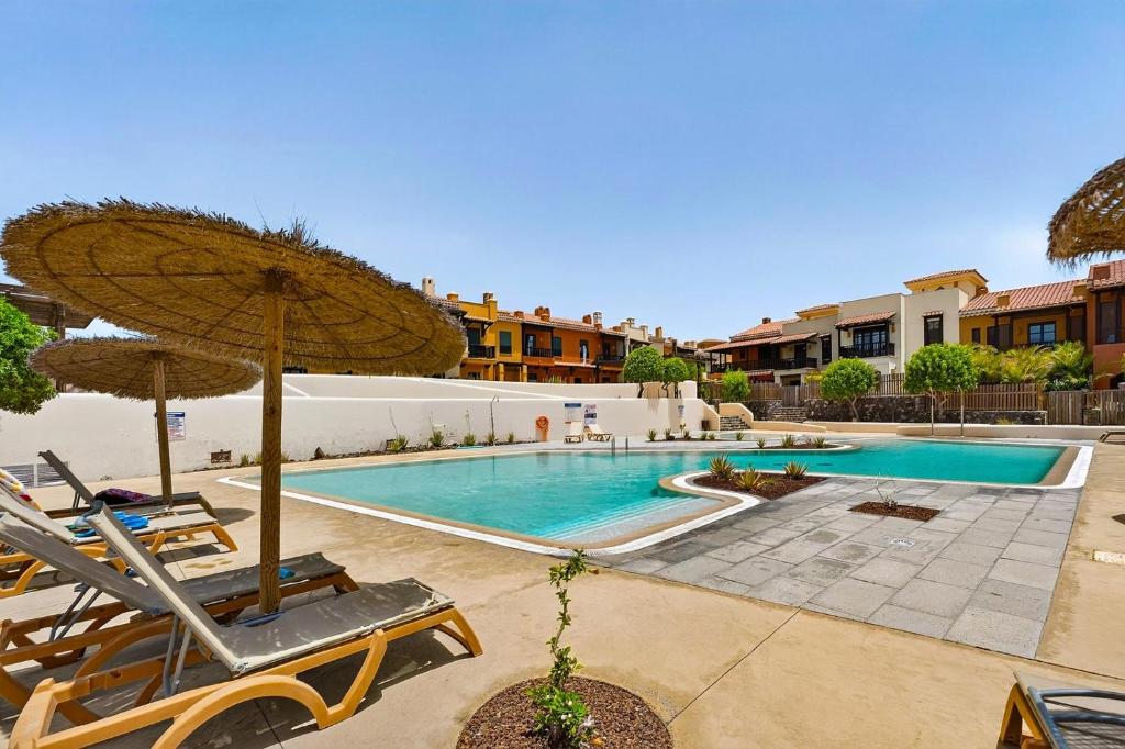 a swimming pool with chairs and an umbrella at Luna in San Blas in San Miguel de Abona
