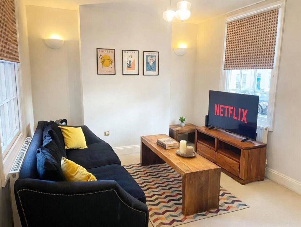 a living room with a blue couch and a tv at Cosy Townhouse in Central Leamington with parking in Leamington Spa