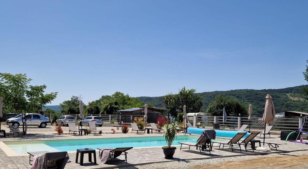 ein Swimmingpool mit vielen Stühlen und Sonnenschirmen in der Unterkunft Casa Legrand in Baziaş