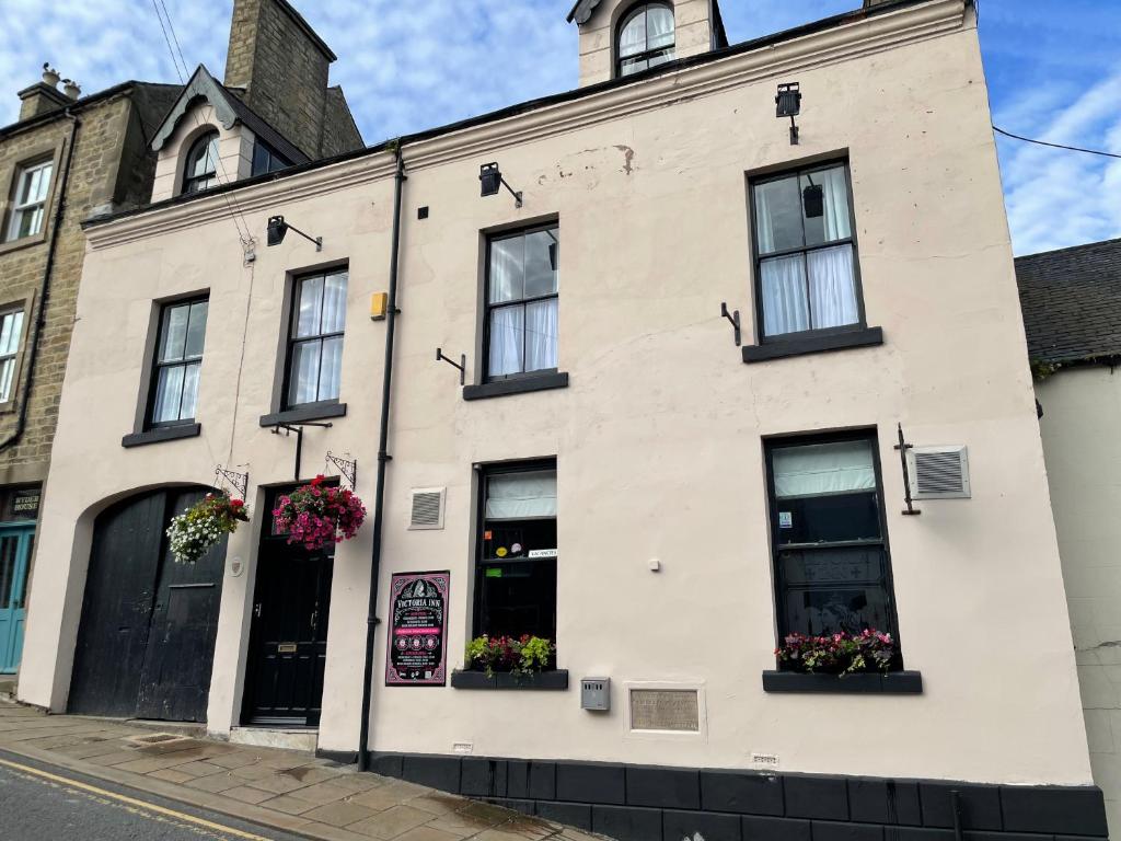 a building on a street with flowers in windows at Victoria Inn in Alston