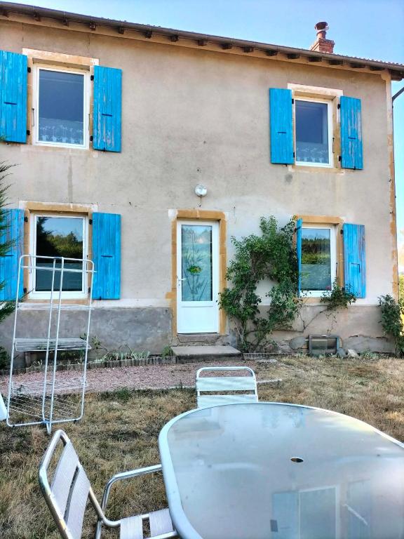 a house with blue windows and a table and chairs at Bienvenu chez moi 