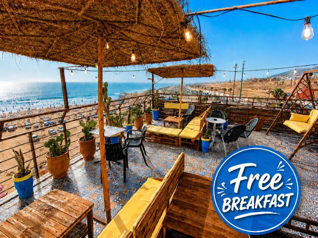 a restaurant with tables and chairs and the beach at Miramar Surf Anza in Agadir