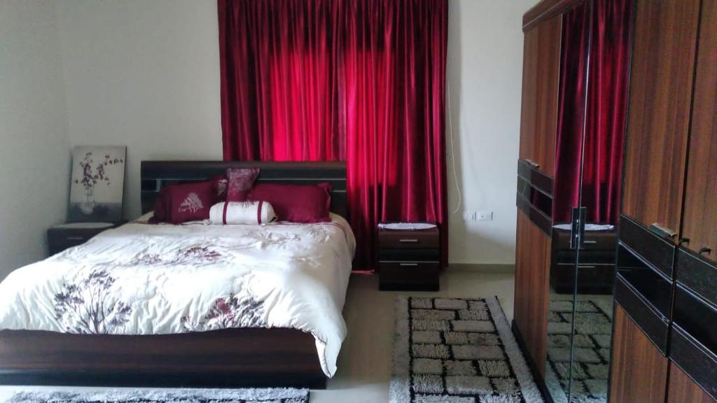 a bedroom with a bed with red curtains at Countryside Guesthouse in Kafr Nabrakh