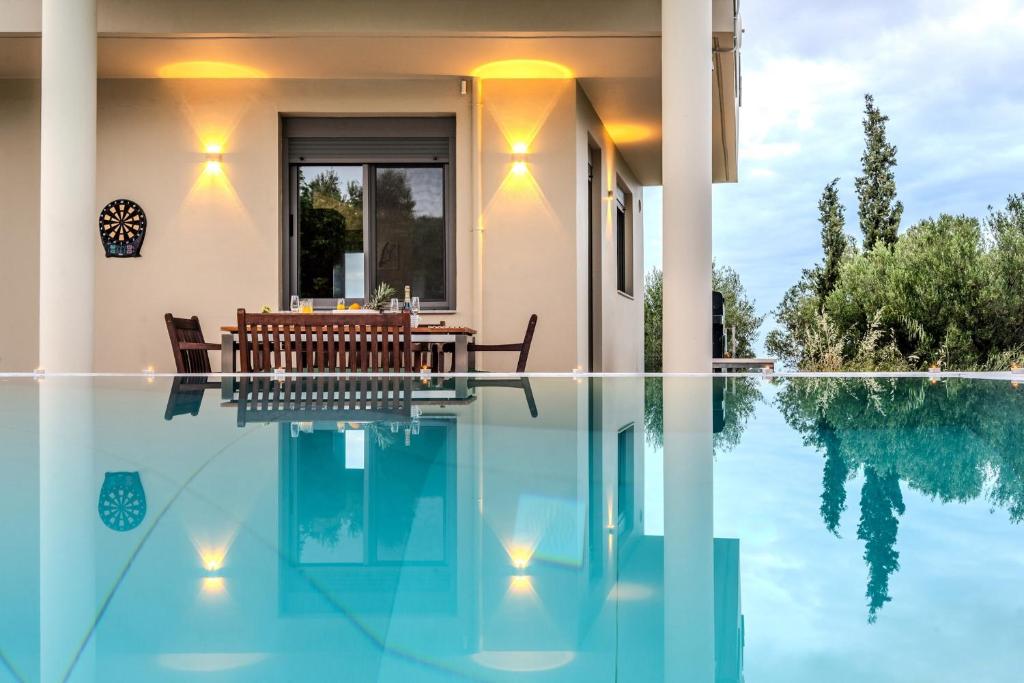 a house with a swimming pool with a table and chairs at Autarke Ökovilla in Agios Myronas