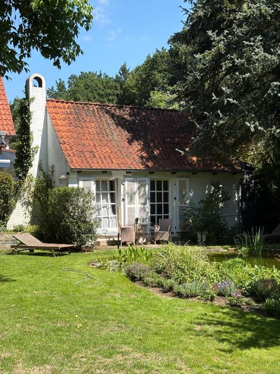 a white house with a red roof and a yard at Ferienhaus Lüneburger Heide mit Therapiemöglichkeit in Jelmstorf