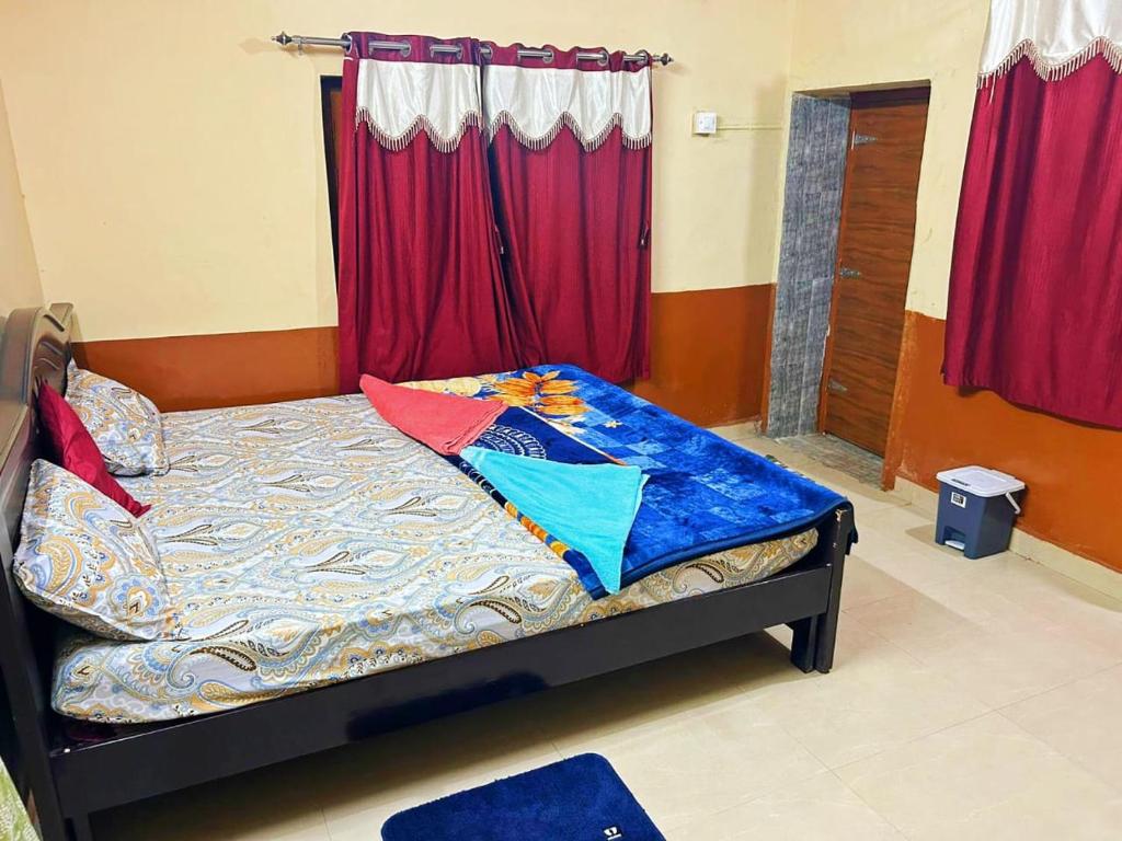 a bedroom with a bed with red curtains at Siddhartha homevibes hampi in Hampi
