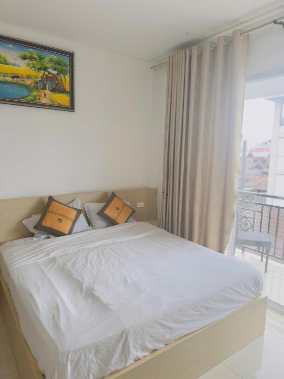 a white bed in a bedroom with a window at Vang Vieng Ha Ha Hotel in Vang Vieng
