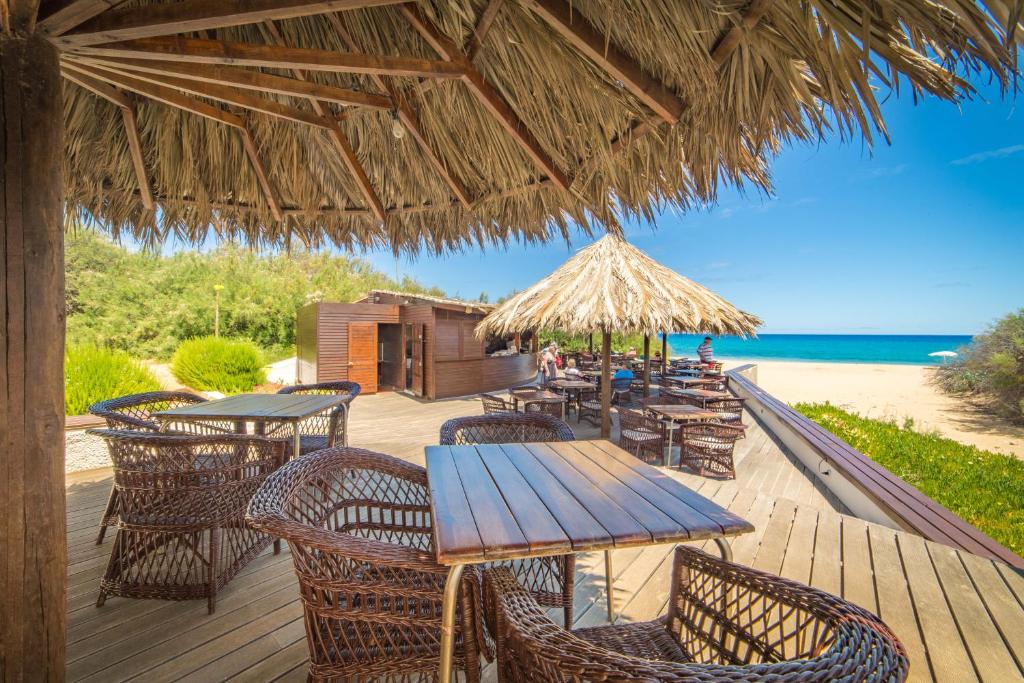 a wooden deck with tables and chairs on the beach at Hotel Porto Santo & Spa in Porto Santo