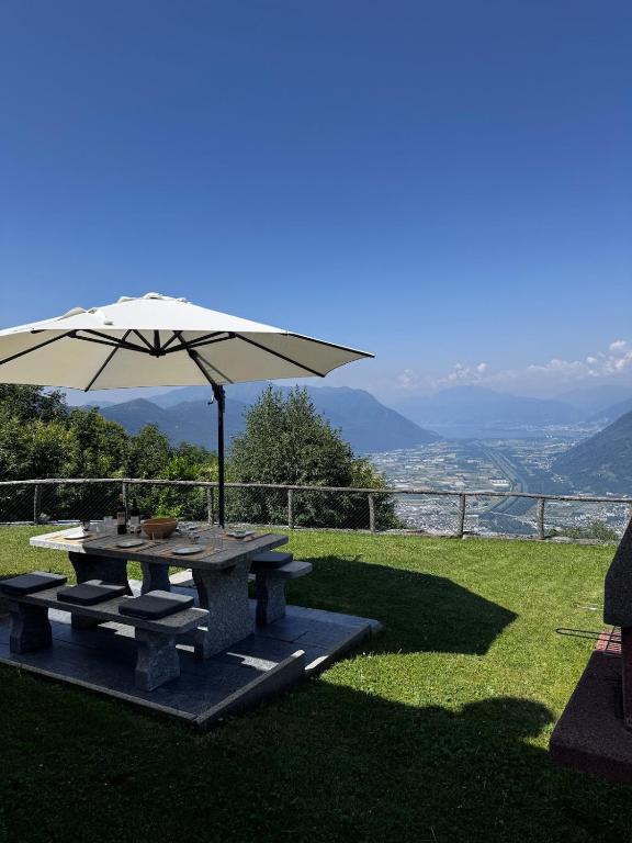 ein Picknicktisch mit Sonnenschirm im Gras in der Unterkunft Casa Prisca in Bellinzona