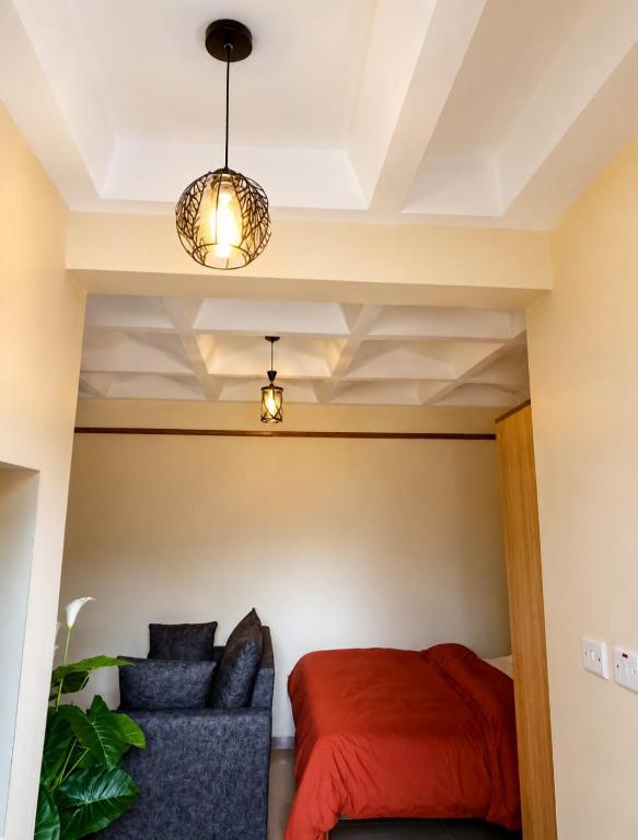 a bedroom with a red bed and a blue couch at Nexus Staycations in Maralal