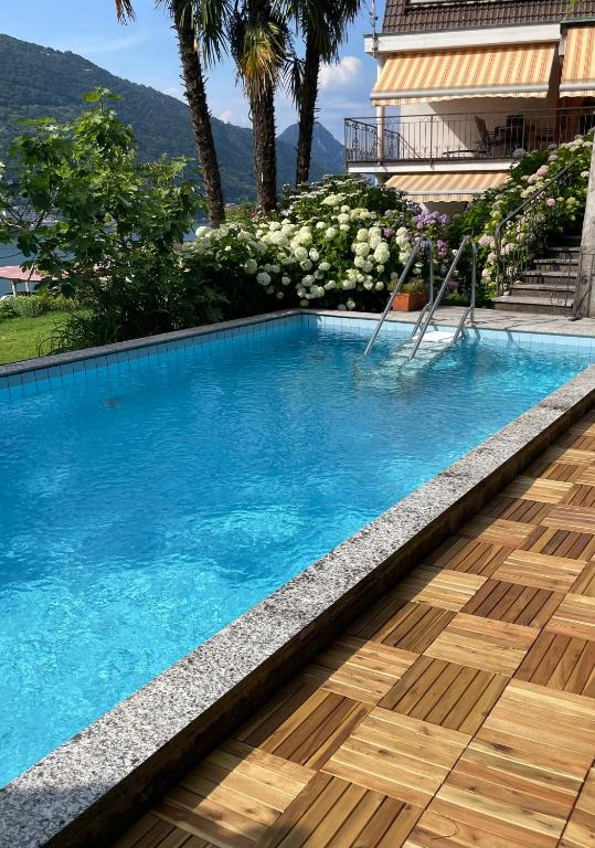 a swimming pool with a wooden floor and a house at Casa Giardinetto in Brusino Arsizio
