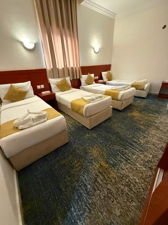 a hotel room with three beds in a room at فندق سما المشاعر اجياد Sama Al Masher Ajyad in Ajyad