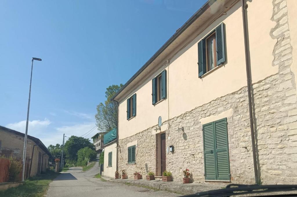 a stone building with green doors and a street at B&B - Casale di Mary in Contigliano