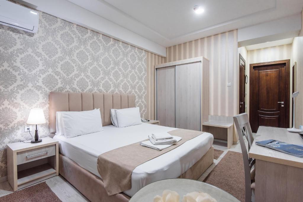 a bedroom with a bed and a table and a desk at Hotel Dream Land Tashkent in Tashkent