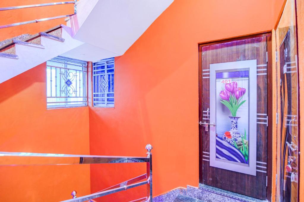 an orange wall with a door with a picture of a flower at Hotel O Elegant Stay CDA in Cuttack