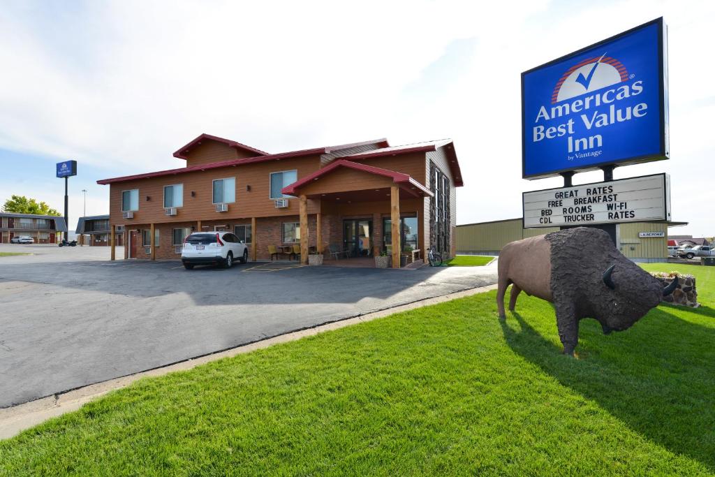 a statue of a cow on the grass in front of a building at Americas Best Value Inn Wall in Wall