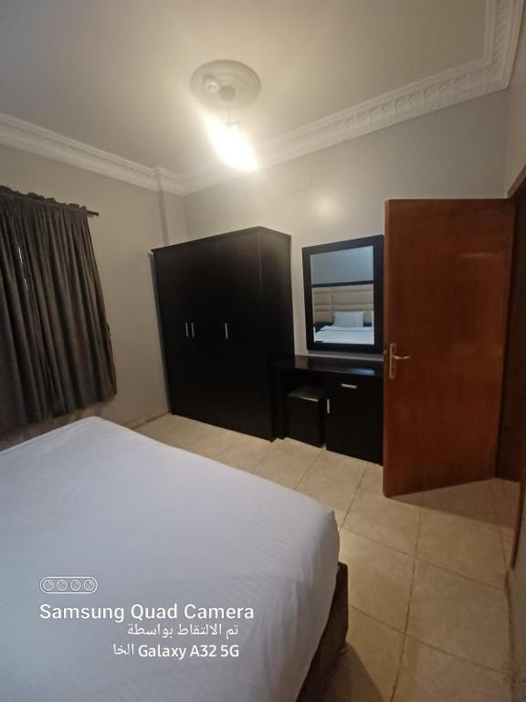 a bedroom with a bed and a flat screen tv at فندق نوارة المنسك in Abha