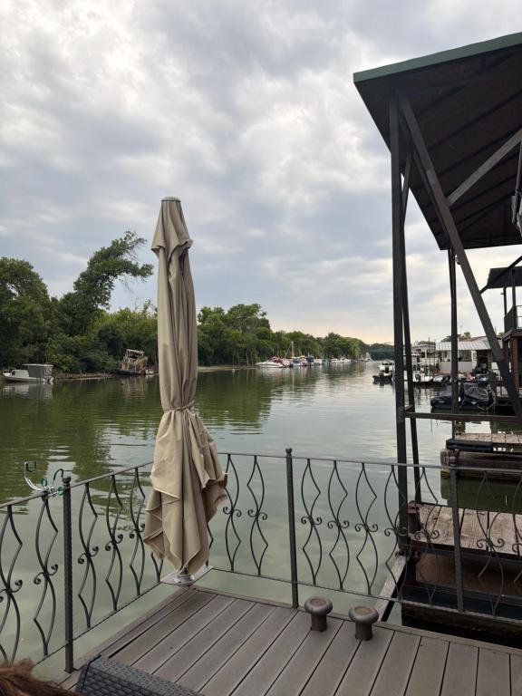 a closed umbrella sitting on a dock next to a river at Vasilisa Luxury River House in Pančevo