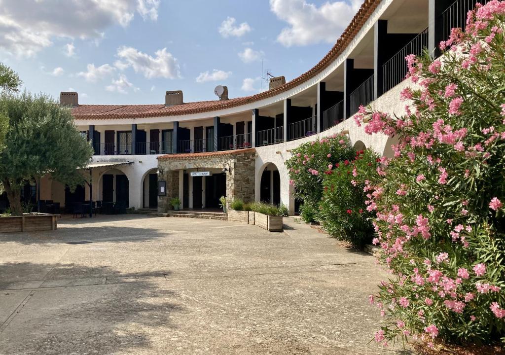 a courtyard of a building with pink flowers at Logis Hôtel Restaurant Le Top du Roulier in Capendu
