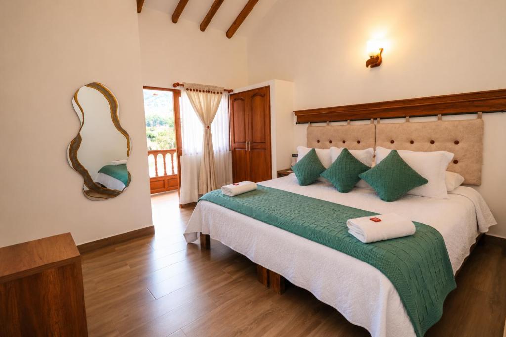 a bedroom with a large bed with a mirror on the wall at Hotel las Palmas in Villa de Leyva