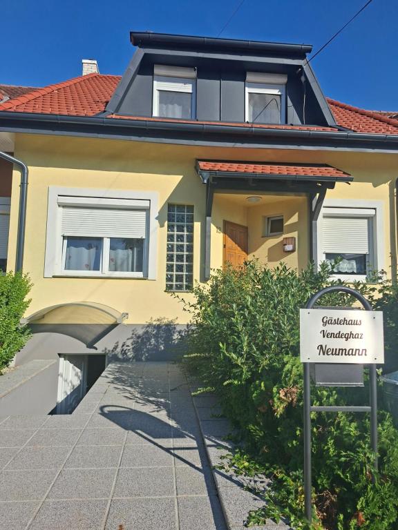 a yellow house with a sign in front of it at Gästehaus Neumann in Bük