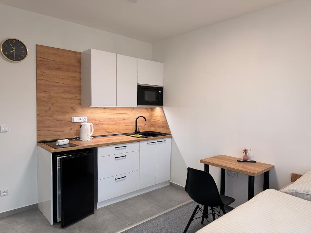 a small kitchen with white cabinets and a desk at Kolík Apartmány in Bohumín
