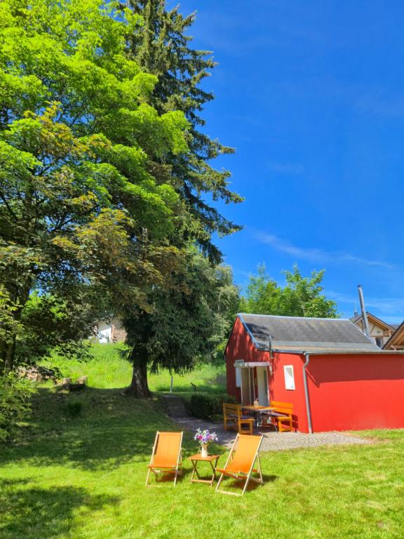 two chairs and a table in front of a red barn at Antonios Hüttenzauber in Oberhof