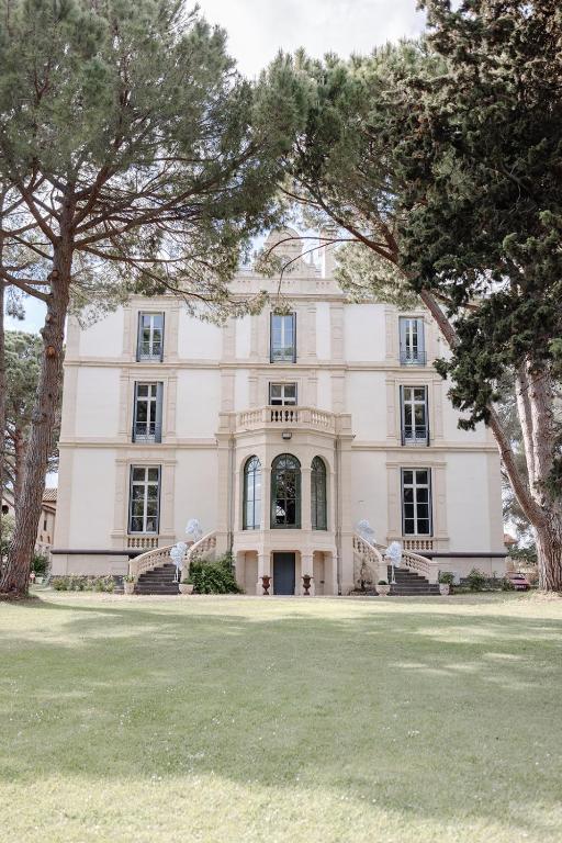 a large white building with trees in front of it at Château de Bayssan in Béziers