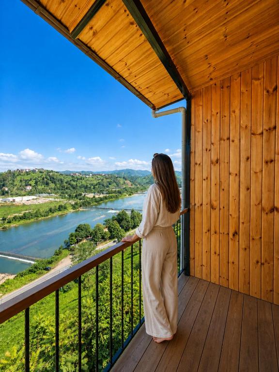 a woman standing on a balcony looking out at a river at Aurora Suit Bungalov in Rize