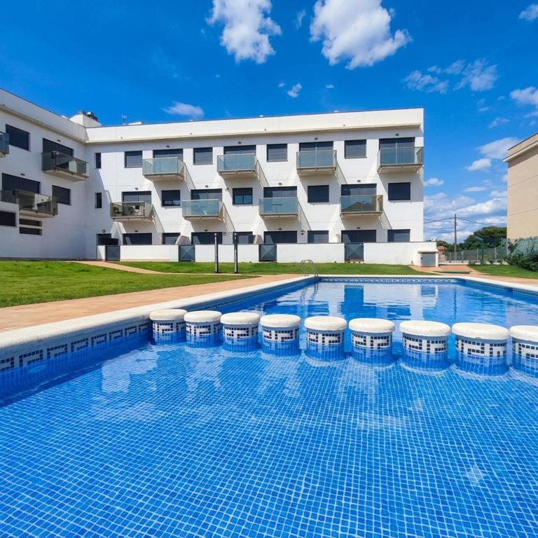 a swimming pool with stools in front of a building at ILDA MENTa in Miami Platja