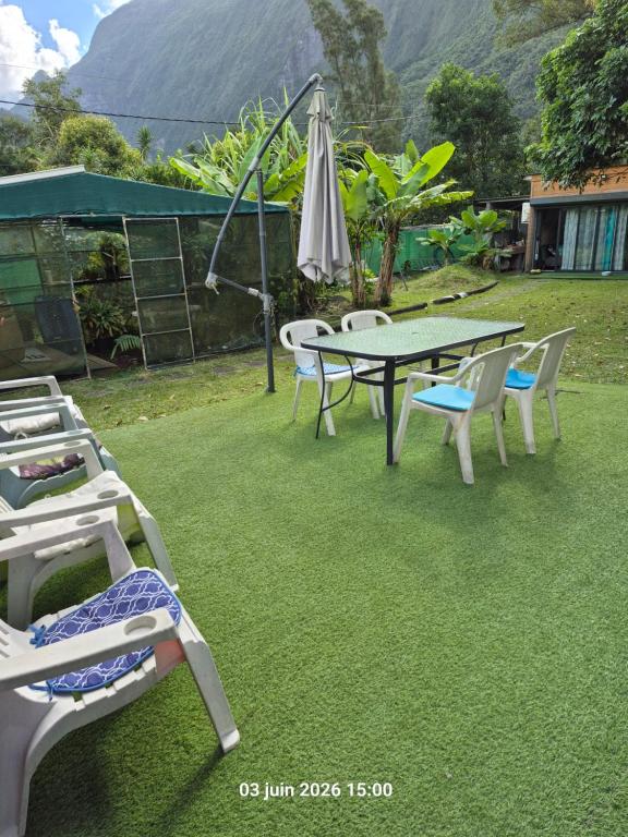 a patio with a table and chairs and an umbrella at La familiale in Salazie