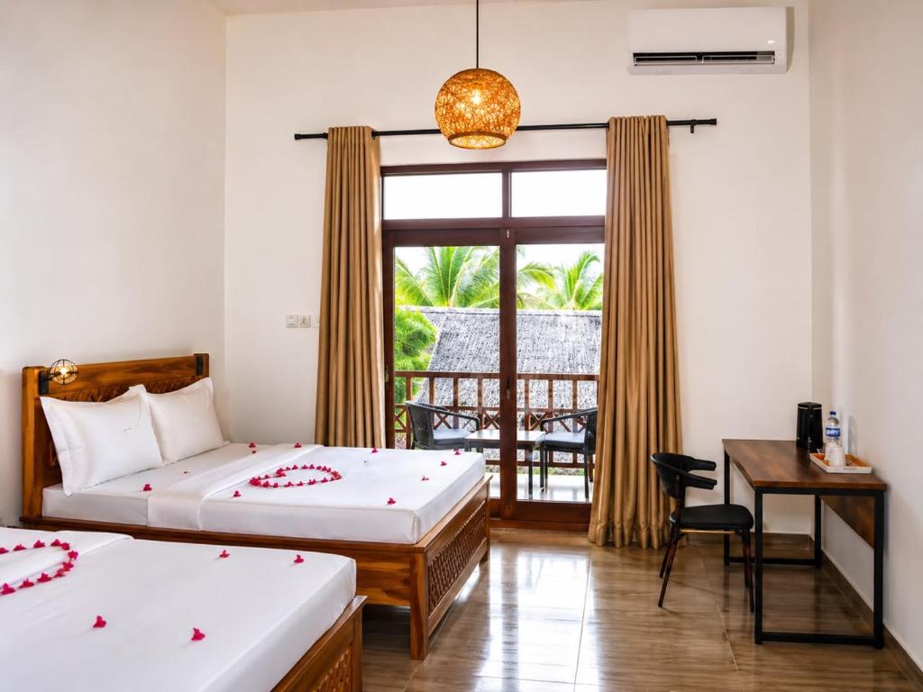 a bedroom with two beds and a desk and a window at The lagoons resort Zanzibar in Nungwi