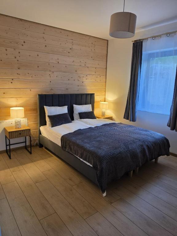 a bedroom with a large bed and a wooden wall at Bieszczady Bóbrka 24 in Bóbrka