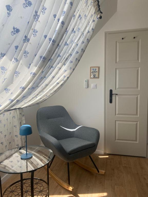 a chair and a table in a room with a window at Hello Apartman in Budaörs