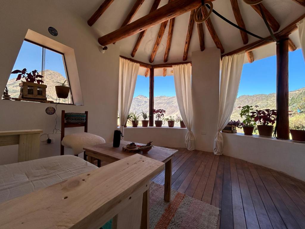 a bedroom with windows and a bed and a table at Cosy Private Room In A Community Home - A Space To Remember You In Andean Mountains in Pisac