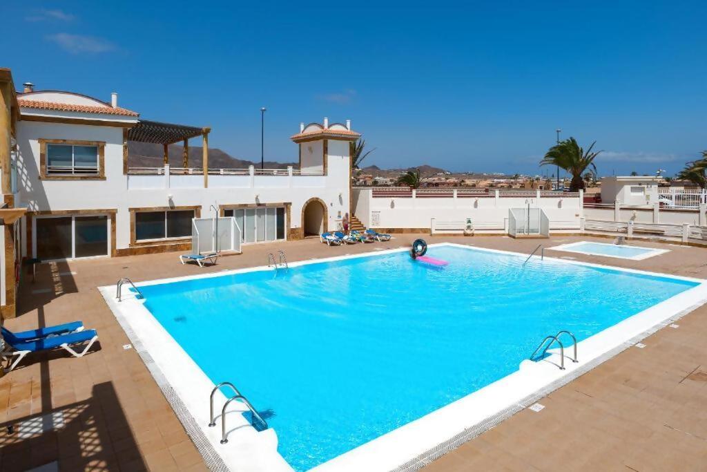 a large swimming pool in front of a building at Casa Girasoles terraza patio aire acondicionado in Corralejo