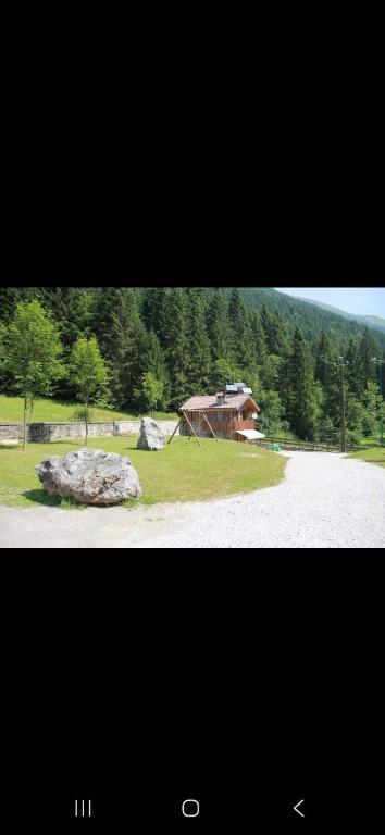 ein Bild von einem Haus und einem Felsen auf einem Feld in der Unterkunft Chalet Laghetti in Schilpario