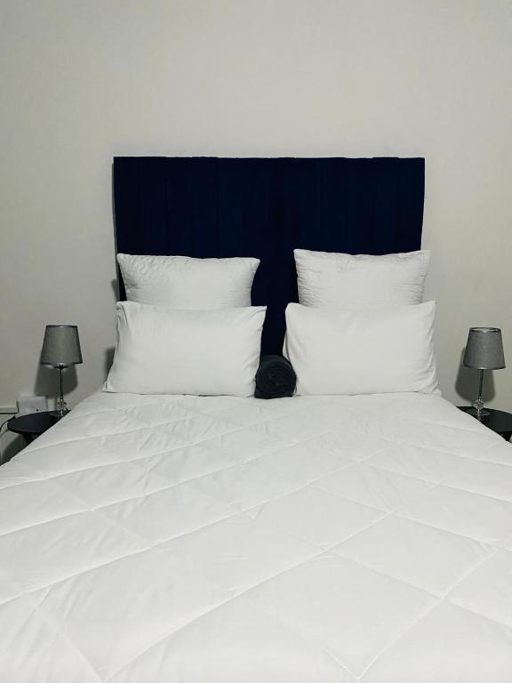 a bed with white sheets and a black cat sitting on it at R&N Hosts Mokhotlong in Mokoeng