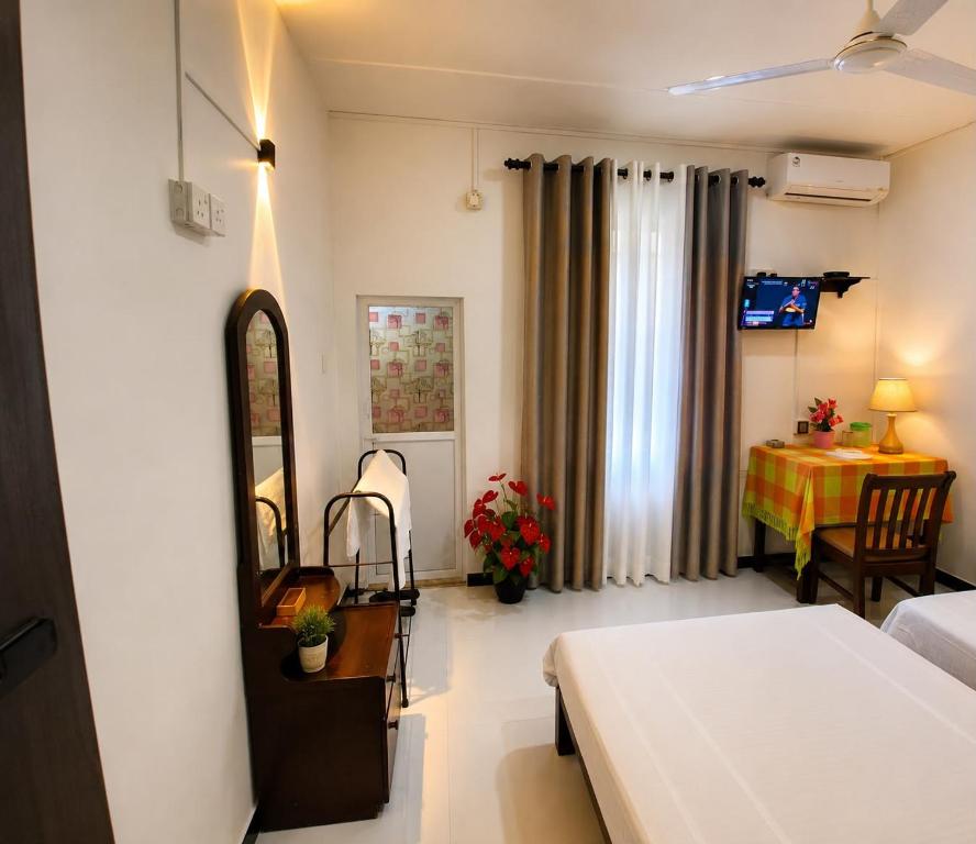 a bedroom with a bed and a table and a mirror at Hotel Kandy Village Inn in Kandy