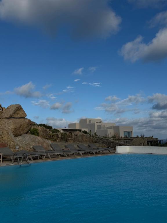 a pool of water with chairs and buildings in the background at Orama Suite II Mykonos Sunset & Pool in Mikonos