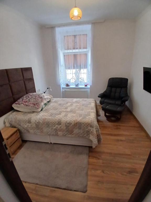 a bedroom with a bed and a chair and a window at Friendly House in Bolesławiec