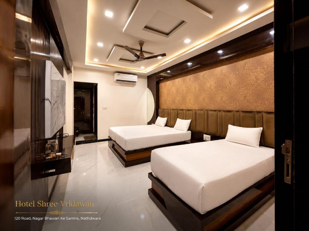 a bedroom with two beds and a tv in it at Hotel Shree Vrindavan in Nāthdwāra