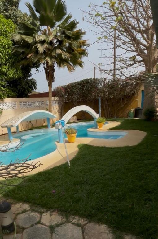 a swimming pool in a yard with a palm tree at Villa Reine Saly in Saly Portudal